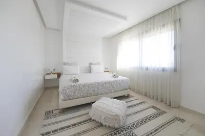 a white bedroom with a bed and a window at DAR KAYIS & LAILA in Marrakech