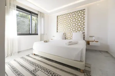 a white bedroom with a large bed and a window at DAR KAYIS & LAILA in Marrakech