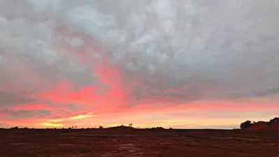 a sunset in a field with a red sky at Bivouac Sahara Passions in Mhamid