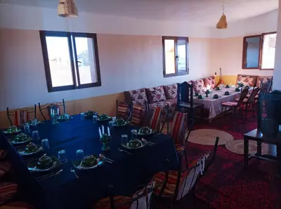 a dining room with a long table and a couch at Bivouac Sahara Passions in Mhamid