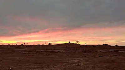 a sunset in the desert with a hill in the distance at Bivouac Sahara Passions in Mhamid