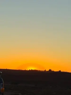 a sunset over a field with a bus in the foreground at Bivouac Sahara Passions in Mhamid
