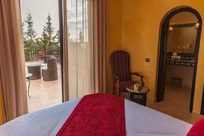 a bedroom with a bed and a view of a balcony at Villa pension complète Marrakech in Marrakech