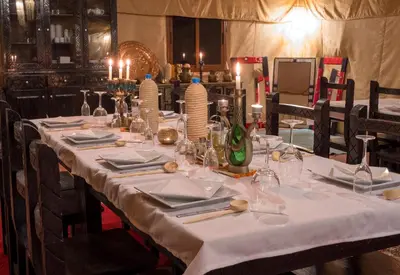 a long table with white table cloth and candles on it at Merzouga Exclusive Camp in Merzouga