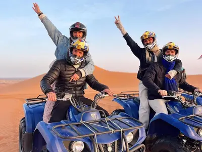 three people on quad bikes in the desert at Merzouga Exclusive Camp in Merzouga