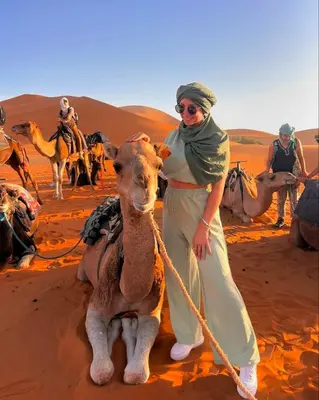 a woman with a camel in the desert at Merzouga Exclusive Camp in Merzouga