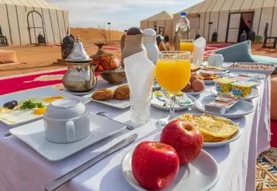 a table with breakfast foods and drinks on it at Merzouga Exclusive Camp in Merzouga