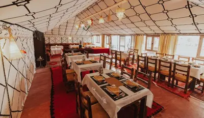 a dining room with tables and chairs in a room at desert luxury merzouga in Merzouga