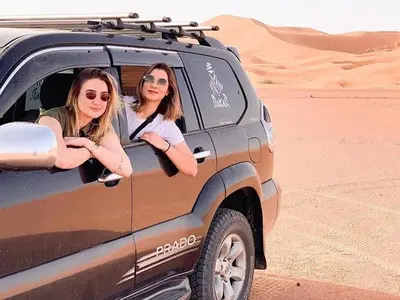two women sitting in the back of a truck in the desert at desert luxury merzouga in Merzouga