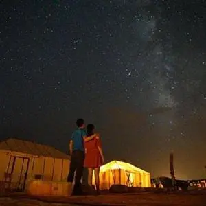 a man and a woman looking at the night sky at desert luxury merzouga in Merzouga