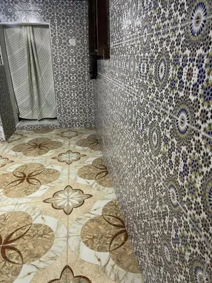 a bathroom with a tiled wall and a mirror at chambres chez Naima Mbarki in Fès
