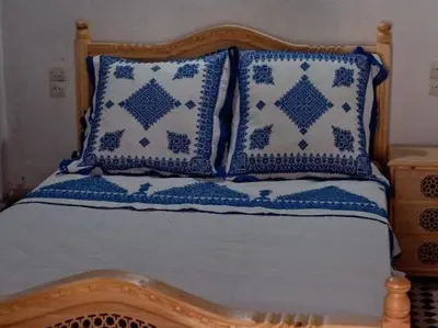 a bed with blue and white pillows on it at suite 3 people Naima mbarki in Fès