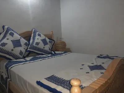 a bed with blue and white pillows on it at suite 3 people Naima mbarki in Fès