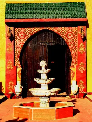 a fountain in front of a building with a gate at Riad Dar Maria in Merzouga