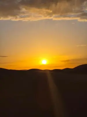 a sunset with the sun setting in the distance at Riad Dar Maria in Merzouga