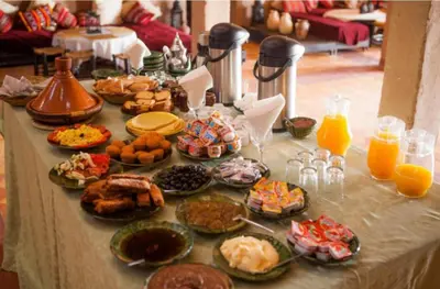 a table with a bunch of food and orange juice at Riad Dar Maria in Merzouga
