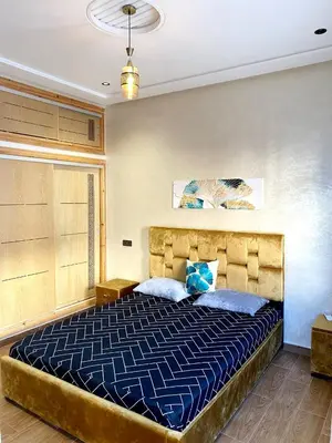 a bedroom with a large bed with a blue comforter at (1) Appartement calme in Fès