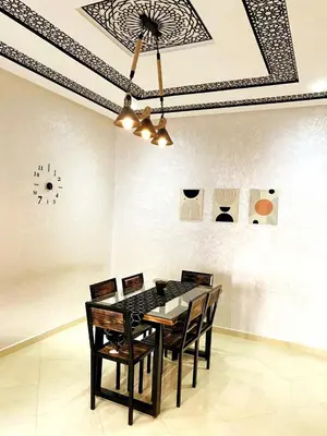a dining room table with chairs and a clock on the wall at (1) Appartement calme in Fès