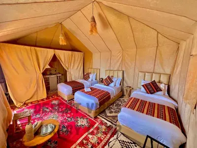 a group of four beds in a tent at Desert vibes Luxury camp in Merzouga