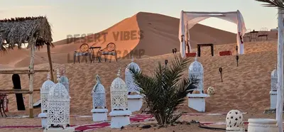 a desert with a tent and a table and chairs at Desert vibes Luxury camp in Merzouga