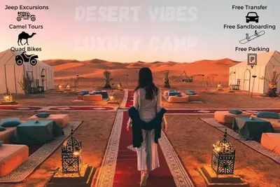 a woman standing in the desert looking at the desert vets luxury camp at Desert vibes Luxury camp in Merzouga