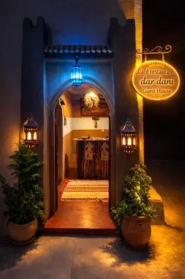an entryway to a dark room with a sign and plants at DAR DANI café restaurant in Boumalne