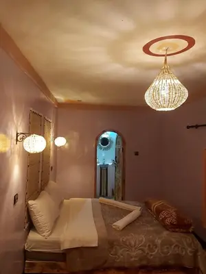 a bedroom with a bed and two chandeliers at DAR DANI café restaurant in Boumalne