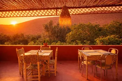 two tables and chairs on a patio with the sunset at DAR DANI café restaurant in Boumalne