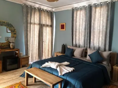 a bedroom with a blue bed and a wooden table at Villa A'Kabar Guest House in Aït Ben Haddou