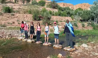 a group of people standing on rocks in a river at Villa A'Kabar Guest House in Aït Ben Haddou