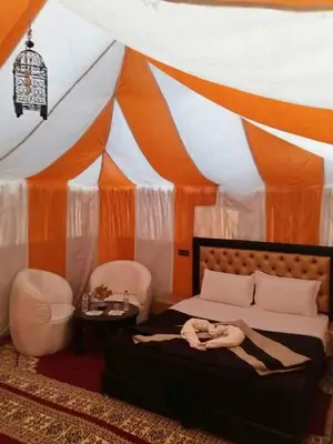 a woman laying on a bed in front of a tent at Merzougadreamcamp in Merzouga