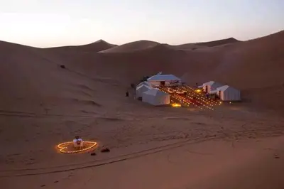a resort in the desert with lights in the sand at Merzougadreamcamp in Merzouga