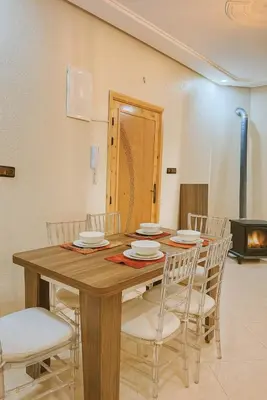 a dining room table with white chairs and a fireplace at Serenity apartments in Azrou