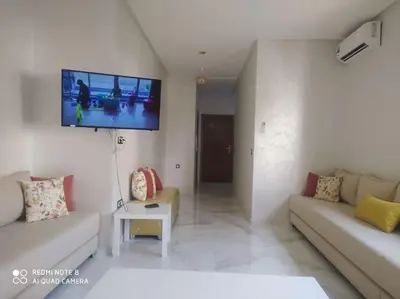 a living room with a couch and a tv on the wall at Luxe & Air Conditionner & Calme appartement in Fès