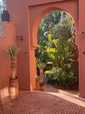 an archway with three palm trees and plants in a room at Maison Amâra Marrakech in Marrakech
