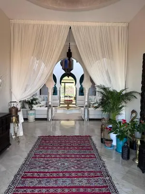 a living room with white curtains and a rug at Maison Amâra Marrakech in Marrakech