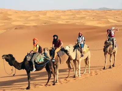 a group of people riding on camels in the desert at Merzouga Berber Camp in Merzouga
