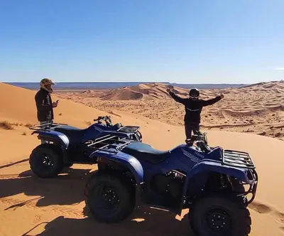 two people standing in the desert with an atv at Merzouga Berber Camp in Merzouga