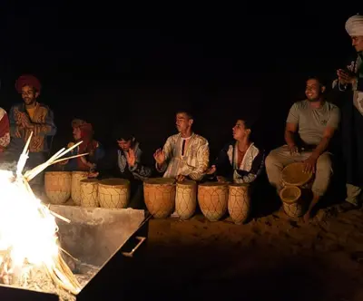 a group of people sitting around a fire at Merzouga Berber Camp in Merzouga