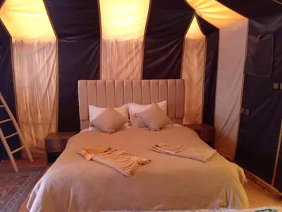 a bed in a tent with two robes on it at Merzouga Berber Camp in Merzouga