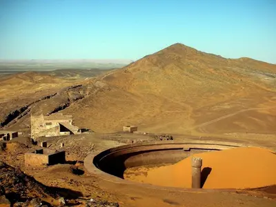 an amphitheater in the desert with a mountain in the background at Merzouga Berber Camp in Merzouga