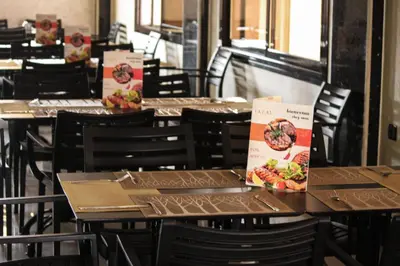a row of tables in a restaurant with menus on them at IAZAL Hotel Ouarzazate in Ouarzazate