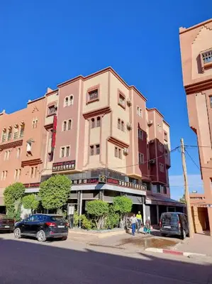 a tall building with cars parked in front of it at IAZAL Hotel Ouarzazate in Ouarzazate