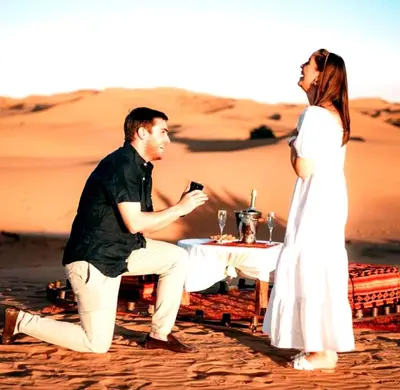 a man and a woman sitting at a table in the desert at Majestic Dunes Luxury Camp in Merzouga