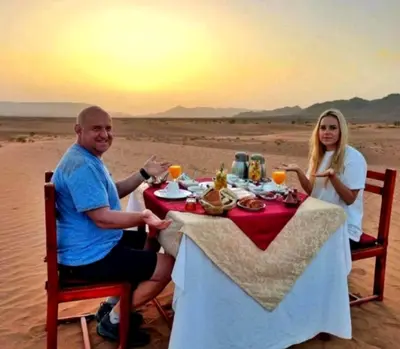 a man and woman sitting at a table in the desert at Majestic Dunes Luxury Camp in Merzouga