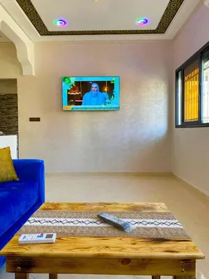 a living room with a blue couch and a tv on the wall at Appartement Calme (1) in Fès