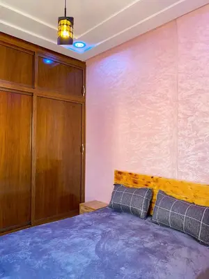 a bedroom with a bed and a wooden cabinet at Appartement Calme (1) in Fès