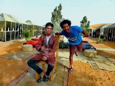 two men are posing for a picture in front of a tent at Majestic Mirage Camp in Merzouga