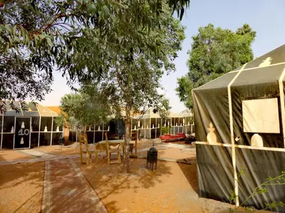 a building with a tent and a dog in a yard at Majestic Mirage Camp in Merzouga