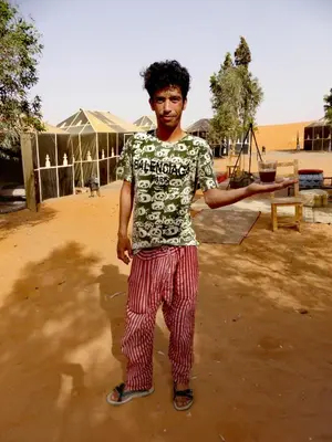 a young man is standing in the dirt at Majestic Mirage Camp in Merzouga